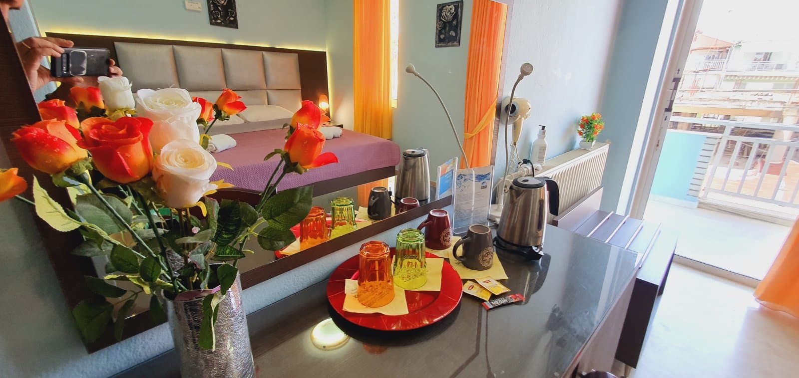 A guest room with a balcony, kettle, fridge and a sofa bed